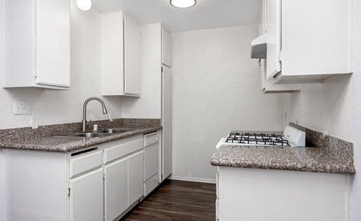 A kitchen with white cabinets and a granite countertop.